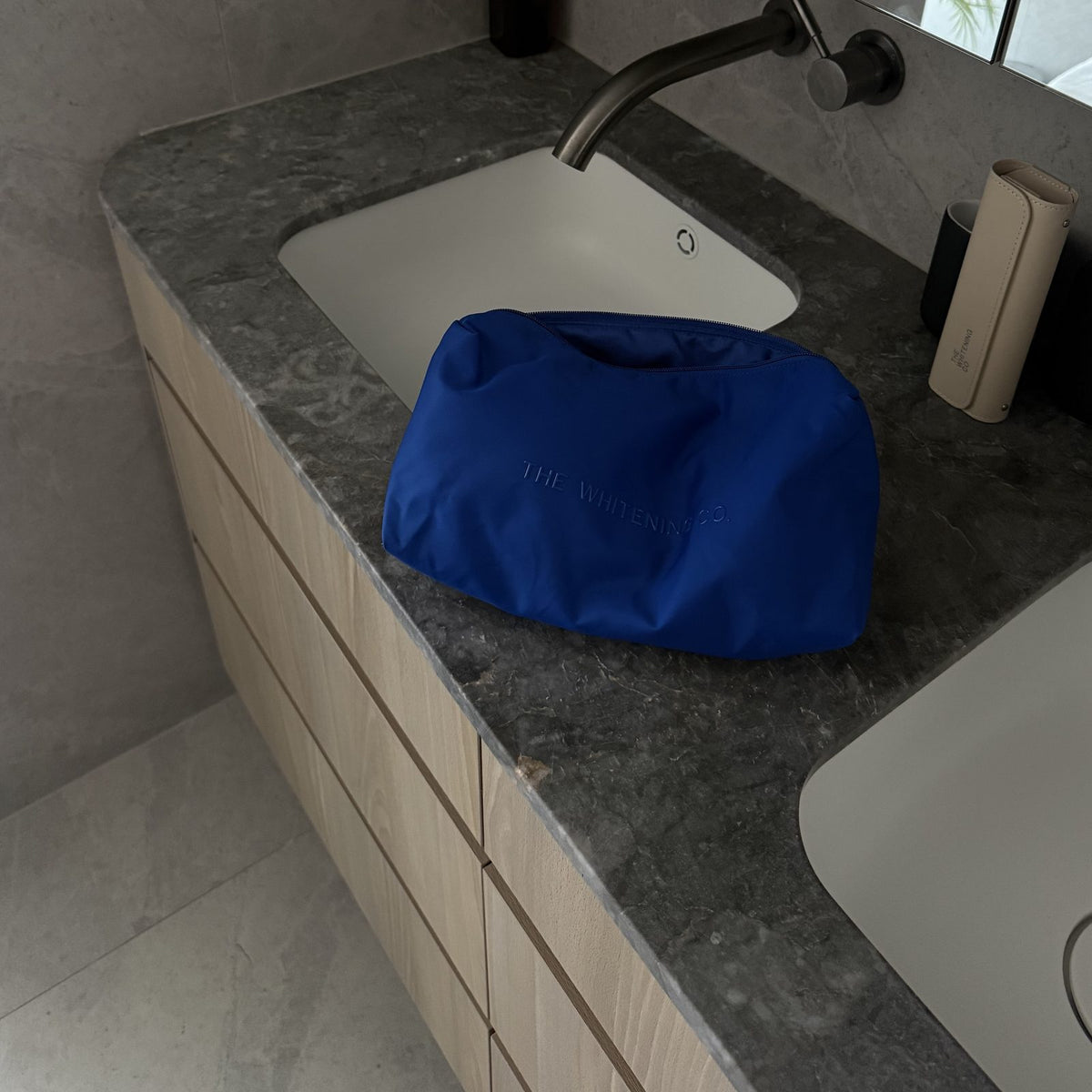The Beauty Bag in Cobalt on a stone bathroom vanity